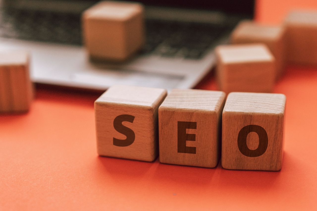 Wooden blocks arranged to spell SEO on a laptop keyboard suggest digital marketing ideas.
